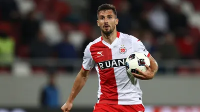 A photorealistic image of a Dinamo Zagreb player, wearing a red and white jersey, with a white shirt and red shorts...