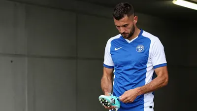 A 35-year-old Dinamo Zagreb midfielder in a plain blue and white jersey, made of a smooth cotton material, stands in the...
