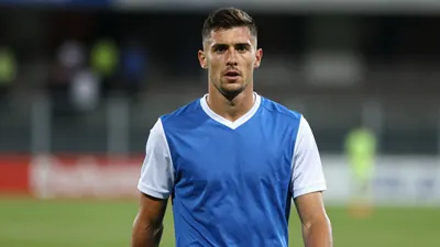 A mid-30s, athletic Dinamo Zagreb midfielder, muscular build, waist-up, face clear and expressive, wearing a plain blue...