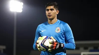 A 26-year-old Mexican goalkeeper with a strong build, wearing a solid blue jersey, photographed with an 85mm f/1.4 lens...