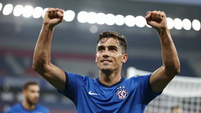 A tight action shot of a Dinamo Zagreb midfielder in a blue kit, celebrating a goal with arms raised