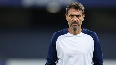 Middle-aged Dinamo Zagreb coach, athletic build, mid-40s, wearing a plain blue and white training top (solid navy...