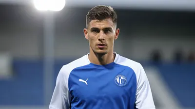 A determined 28-year-old Dinamo Zagreb midfielder, athletic build, in a plain blue and white training top, waist-up...
