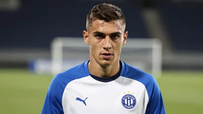 A determined, athletic 25-year-old Dinamo Zagreb midfielder, in a plain blue and white training top, intense eyes locked...