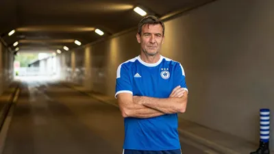 A 35-year-old, 5'10" Dinamo Zagreb media relations staff member, wearing a plain blue and white polyester training top...