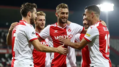 A photorealistic image of GNK Dinamo Zagreb's midfielder Beljo celebrating his goal with his teammates, wearing a red and...