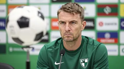 A photo of the Kauno Žalgiris coach, taken during a press conference in Kaunas, Lithuania, with a serious expression and...