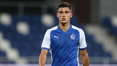 A determined 28-year-old Dinamo Zagreb midfielder, athletic build, in a plain blue and white jersey, intense eyes...