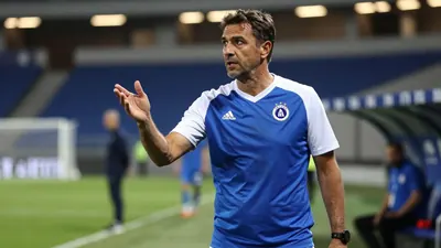 A 35-year-old male Dinamo Zagreb assistant coach, with a rugged, weathered complexion, stands intensely on the edge of...