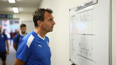 A 35-year-old, 5'9" male coach in a blue and white striped training top, standing in the tunnel at Stadion Maksimir...