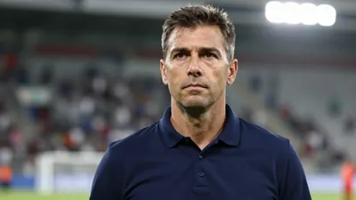 Photorealistic head-and-shoulders of a focused 30-40 year old male football coach in a solid navy blue polo shirt...