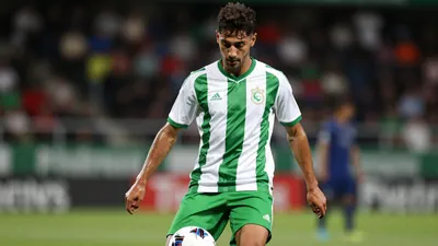 A photorealistic image of a 21-year-old midfielder in a green and white jersey, with a white ball at his feet, taken with...