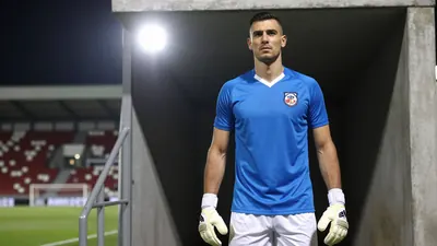 A photorealistic image of a 25-30 year old, athletic, clean-shaven, dark-haired, dark-eyed, male football goalkeeper...