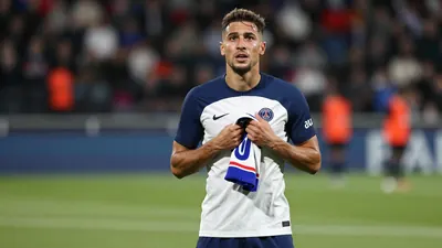 Mid-30s French midfielder, lean build, hair slightly tousled, eyes glistening, wearing a plain blue and white training...