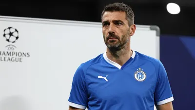 A 35-year-old male Dinamo Zagreb assistant coach with a strong build, wearing a blue jersey with white fabric, standing...