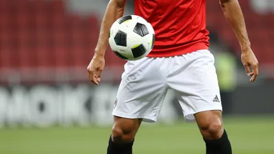 A photorealistic image of an anonymous Dinamo Zagreb player in a red jersey with white shorts and black socks, taken with...