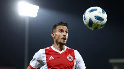 A photorealistic image of a Dinamo Zagreb player in a red and white jersey, shot with a 85mm f/1.4 lens, with a shallow...
