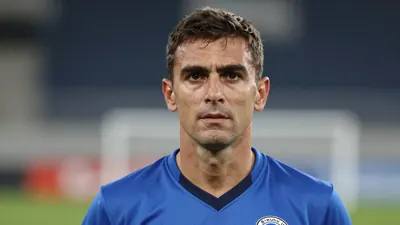 A mid-30s anonymous male coach in a solid blue Dinamo Zagreb kit, head-and-shoulders shot, background blurred