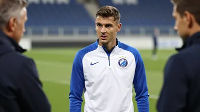 A focused 25-year-old midfielder in Dinamo Zagreb's blue and white training top, standing pitchside at Stadion Maksimir...
