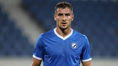 Mid-30s muscular Dinamo Zagreb player, head-and-shoulders, intense gaze, sweat glistening on brow, wearing plain unmarked...