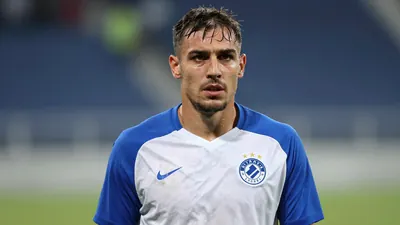 Mid-30s Dinamo Zagreb forward, muscular, intense expression, head-and-shoulders, wearing a plain blue and white training...