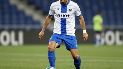 A photorealistic image of an anonymous Dinamo Zagreb player in a white jersey with a blue stripe, wearing a blue pair of...