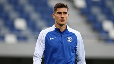 Mid-30s athletic midfielder, lean build, intense gaze, wearing a plain, unmarked training top of Dinamo Zagreb’s home...