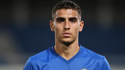 Photorealistic head-and-shoulders shot of a 25-30 year old athletic male forward in a solid blue jersey, smooth fabric...