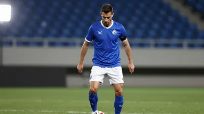 A photorealistic image of an anonymous Dinamo Zagreb player in his mid-20s, wearing a blue jersey with a white collar and...