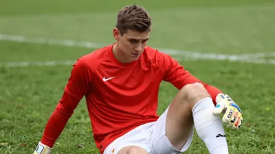 A tight waist-up crop of a young, anonymous, 26-year-old goalkeeper in a red jersey with white shorts and white socks...