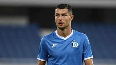 Mid-30s male Dinamo Zagreb player, athletic build, waist-up in a plain blue shirt with white trim, fabric smooth and...