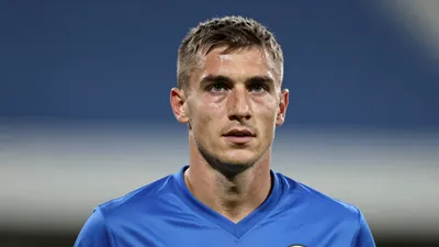 A mid-30s anonymous Dinamo player in a solid blue kit, head-and-shoulders, captured with an 85mm lens at f/1.4...